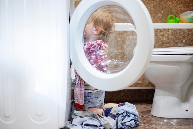 Niño en el baño con lavadora niño ayudando con las tareas familiares