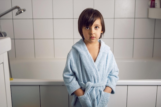 Foto un niño con una bata de baño azul está en el baño después de un spa