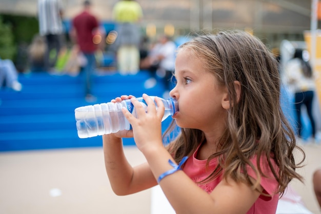 Niño bebe agua de una botella de plástico al aire libre