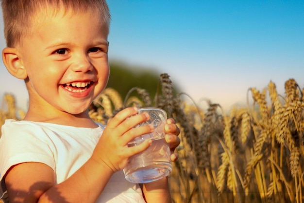 Un niño bebe agua en el fondo del campo