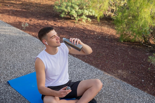 Un niño bebe agua mientras hace ejercicio al aire libre concepto de hidratación en el deporte