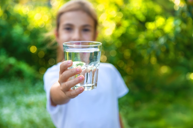 El niño bebe agua de un vaso. Enfoque selectivo. Niño.