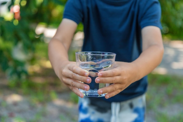 El niño bebe agua de un vaso Enfoque selectivo