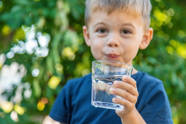 El niño bebe agua de un vaso Enfoque selectivo