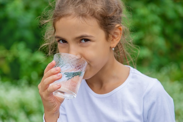 Foto el niño bebe agua de un vaso. enfoque selectivo.