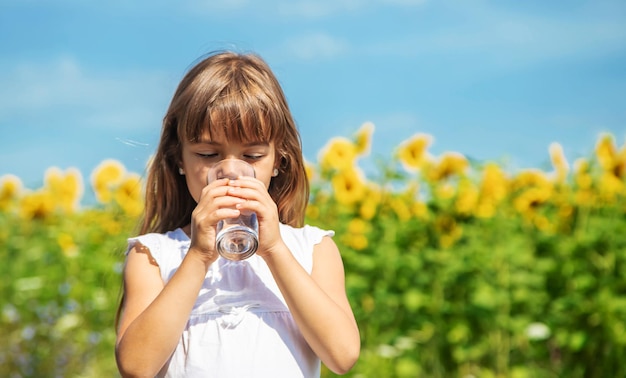 El niño bebe agua de un vaso. Enfoque selectivo.