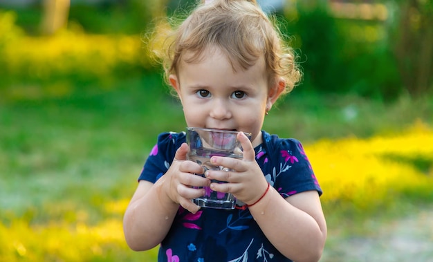 El niño bebe agua de un vaso Enfoque selectivo