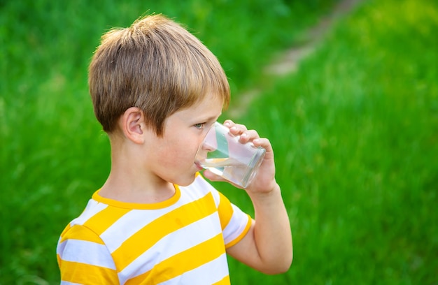 Niño bebe agua de un vaso.