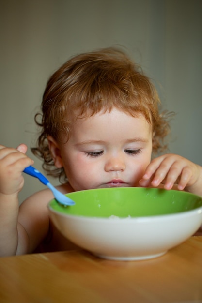 Niño bebé comer sopa en la cocina con platos y cuchara concepto de nutrición infantil