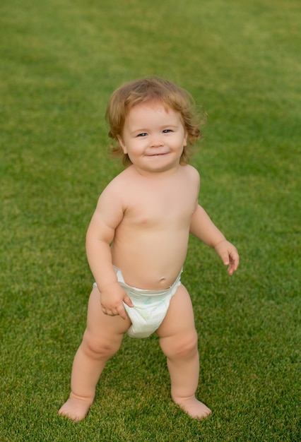 Niño bebé divertido en pañales jugando en el campo de hierba verde estilo de vida de los niños al aire libre de verano