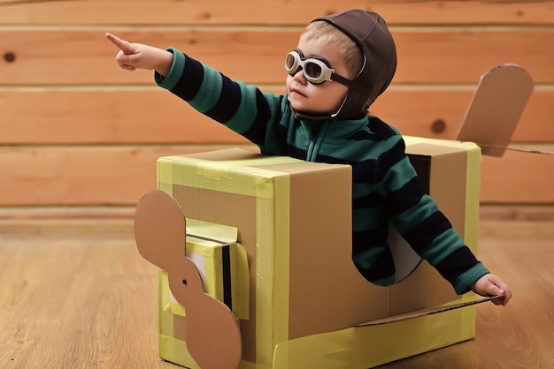 El niño bebé es piloto. Niños viajan, imaginación. Niño niño juega en avión de cartón, infancia. Entrega de correo aéreo, construcción de aviones. Aventura de ensueño.