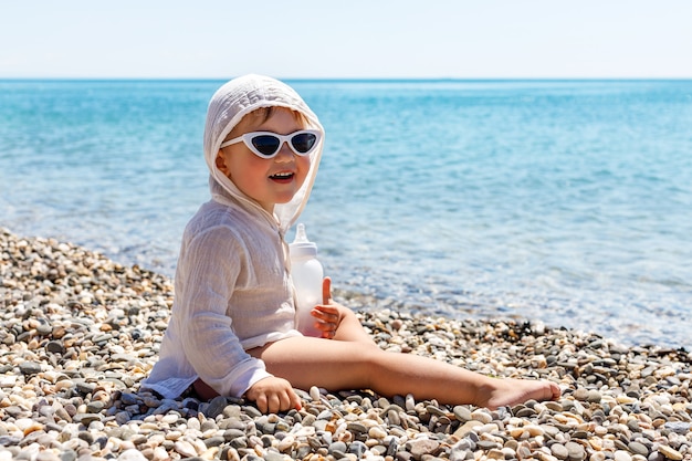 Niño bebé feliz sonríe en el mar en verano