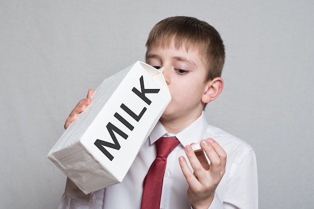 Niño bebe de un gran paquete de leche blanca