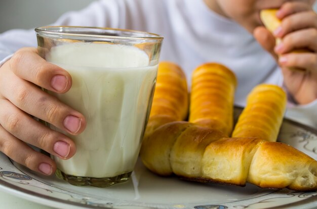 Un niño bebe leche y come salchichas en masa.