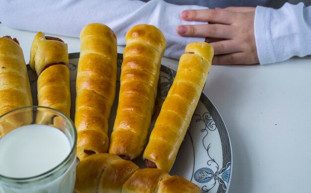 Un niño bebe leche y come salchichas en masa.