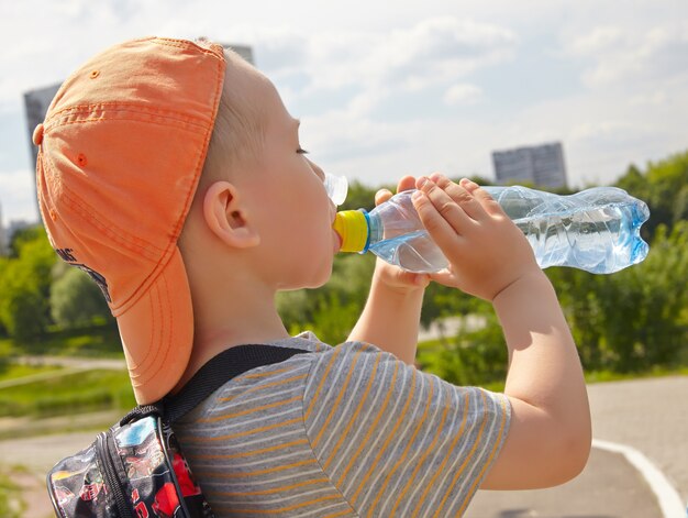 Niño bebiendo agua en el parque.