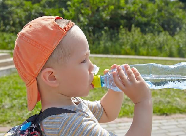 Niño bebiendo agua en el parque.