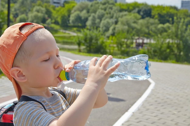 Niño bebiendo agua en el parque.