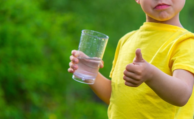 Niño bebiendo agua con un vaso en el parque