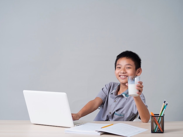 Niño bebiendo leche mientras estudia en línea en casa