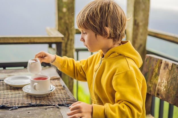 Niño bebiendo té en un café en las montañas