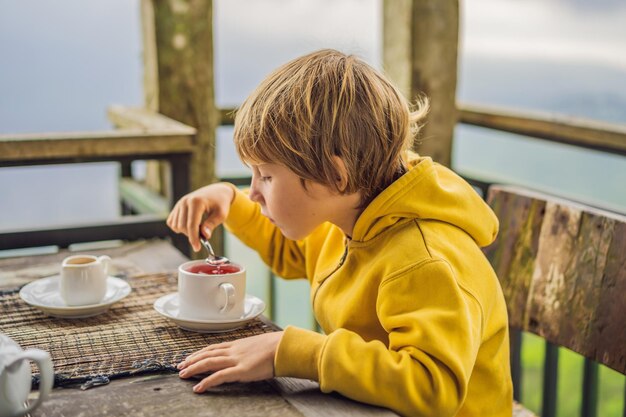 Niño bebiendo té en un café en las montañas