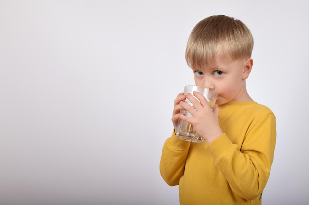 Un niño bebiendo un vaso de agua.