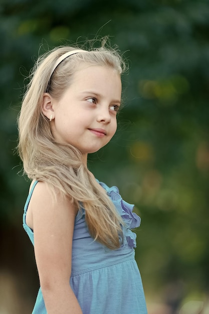 Niño de belleza con cabello largo y rubio en el día de verano