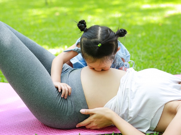 Niño besando el vientre de la madre embarazada en el jardín