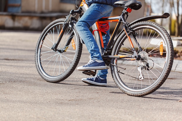 Niño en una bicicleta en la carretera de asfalto en día soleado de primavera.