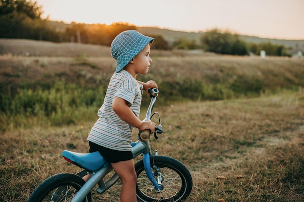 Niño en bicicleta en la carretera en el campo mirando a otro lado el día internacional del niño