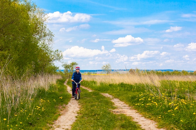 Niño en bicicleta en carretera en día soleado