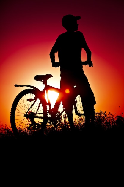 Foto niño en bicicleta en el fondo del atardecer