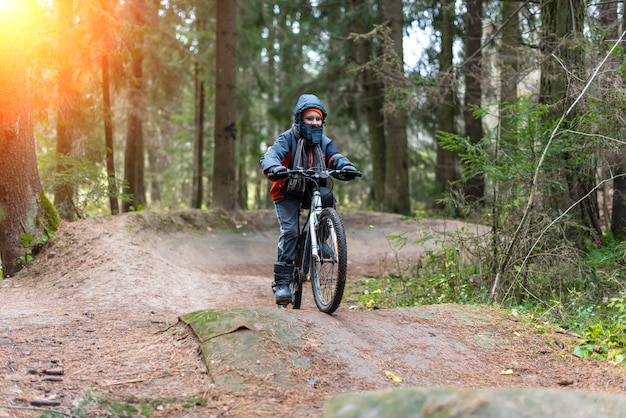 Niño en bicicleta en el otoño en el bosque