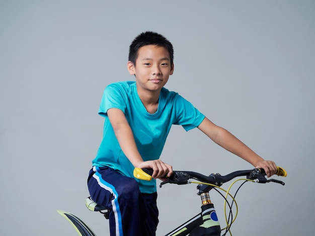 Niño con bicicleta sobre fondo gris