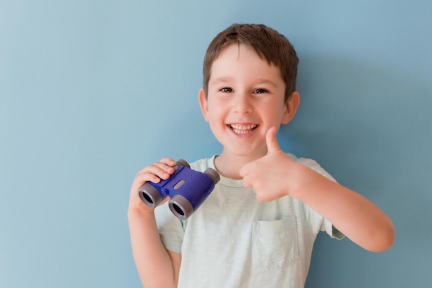 Niño con binoculares sobre fondo azul.