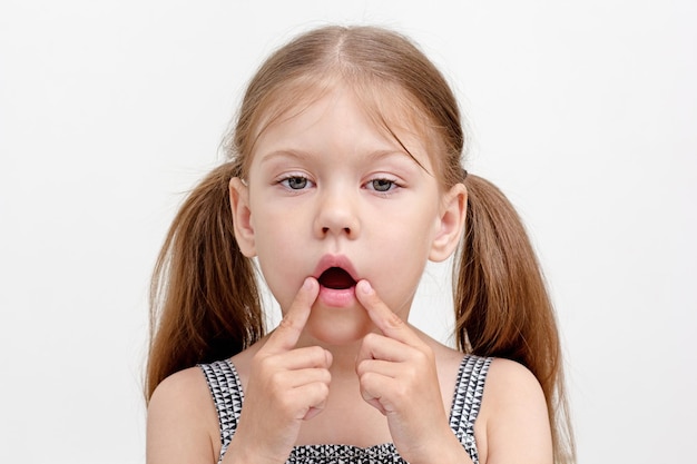 Foto niño con la boca abierta y los dedos en la esquina de la boca