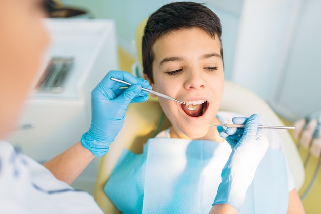 Niño con la boca abierta en un sillón dental