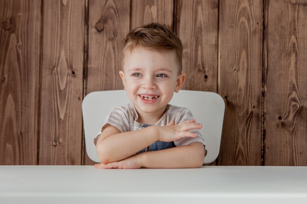 Un niño bonito está sentado a la mesa. De cerca