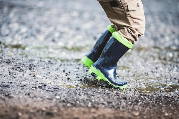 Foto niño con botas de goma en clima lluvioso