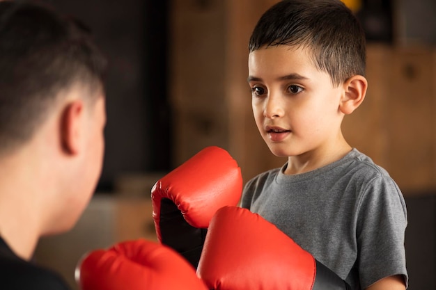 Niño boxeando con guantes rojos dentro del concepto de coraje y esfuerzo