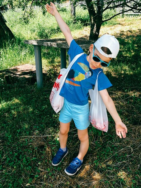 Foto niño con los brazos extendidos de pie en el campo de hierba