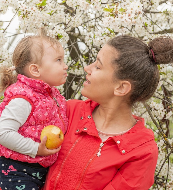 El niño en brazos de la niña mira las flores.