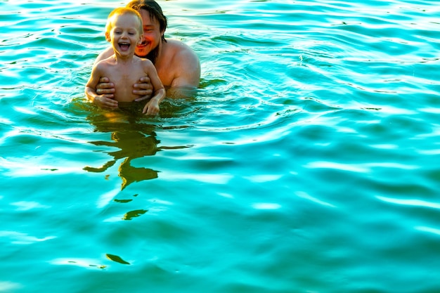 El niño en brazos de su padre en las olas del mar Papá con el niño pequeño de vacaciones