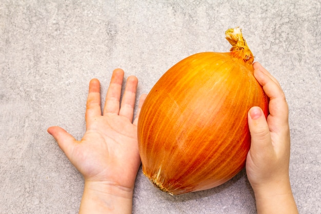 Niño con bulbo de cebolla gigante fresca