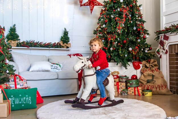 Niño a caballo cerca del árbol de Navidad Enfoque selectivo