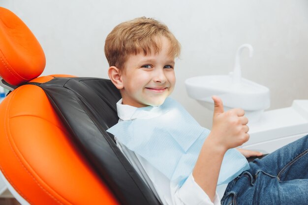 Un niño con cabello rojo rizado en una silla dental muestra la clase de odontología infantil