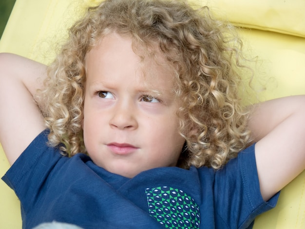 Niño con cabello rubio rizado, afuera