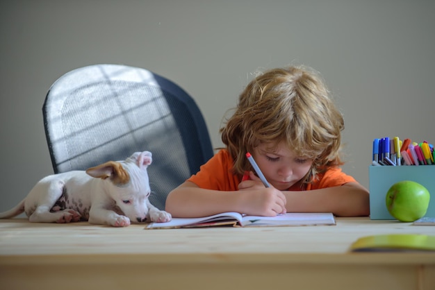 Niño con cachorro de mascota haciendo los deberes escolares