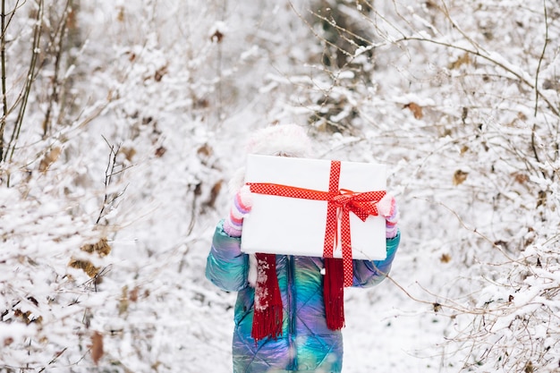 Niño con caja de regalo. Niña con caja de regalo de Navidad en invierno al aire libre en vísperas de Navidad.